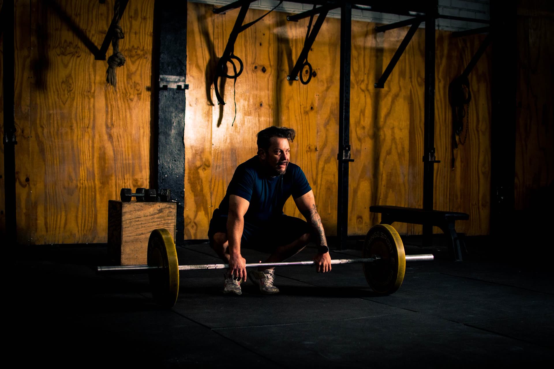 Athlete setting up a barbell deadlift in a dim gym